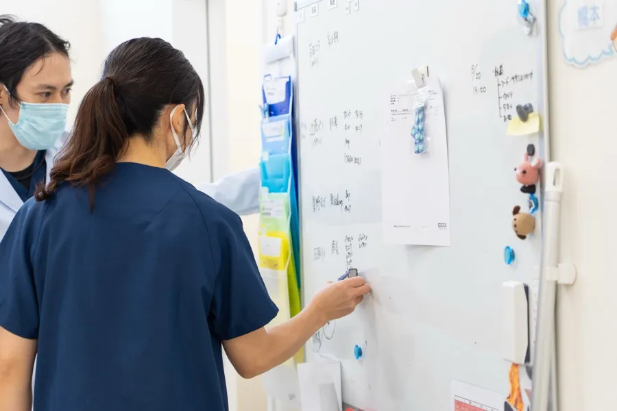 ホワイトボードの前で予定を書き入れるスタッフ