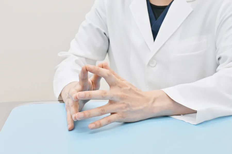 診察台に手を置いて症状をうかがう様子